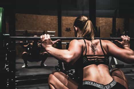 A woman squats with a barbell on her shoulders