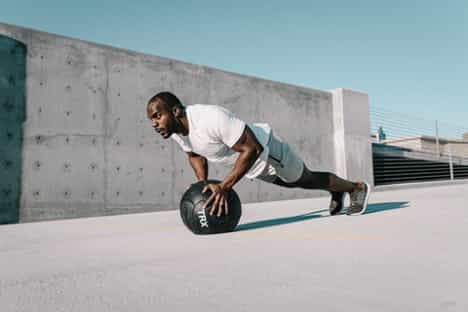 A man performs a push up with a medicine ball